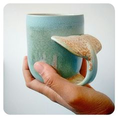 a hand holding a blue and green coffee cup with a starfish on it's side