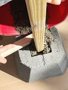 a person is using a knife to cut wood into pieces with cement in the background