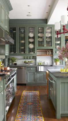 a kitchen filled with lots of green cabinets and counter top space next to a rug on the floor