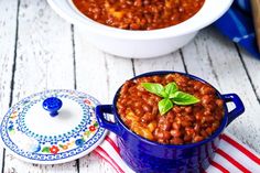 a bowl of baked beans with basil on top