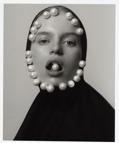 a black and white photo of a woman with pearls on her head, making a surprised face