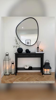 a black console table with candles and a round mirror