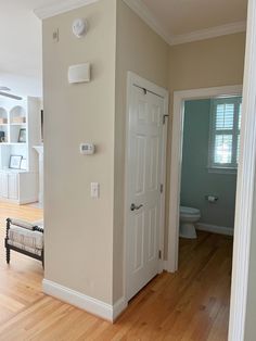 an open door leading to a bathroom and living room with hard wood flooring in the foreground