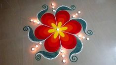 a decorated floor with candles on it and a red flower surrounded by white lights in the center