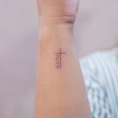 a woman's arm with a small cross tattoo on the left side of her wrist