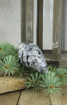 an ornament sitting on top of a wooden table next to pine cones and needles