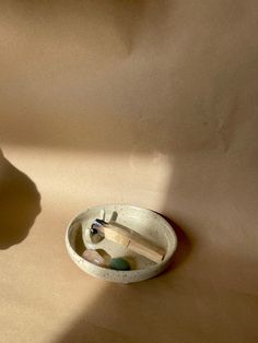 a small white bowl sitting on top of a counter next to a wooden spoon and toothbrush holder