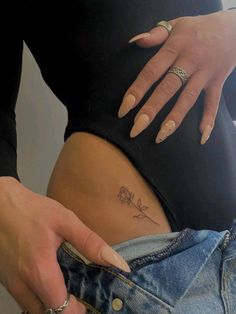 a woman's stomach with a small flower tattoo on her left side ribcage