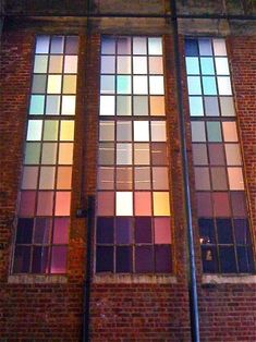 the side of a building with two windows that have multicolored squares on them