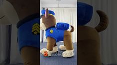 an inflatable dog wearing a blue shirt is standing on the floor next to curtains