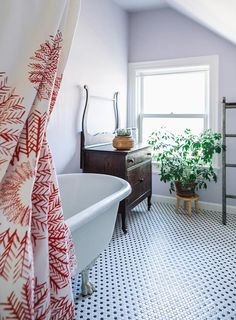 a bathroom with a bathtub, toilet and plant in it's corner next to the window