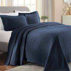 a bed with blue sheets and pillows in a bedroom