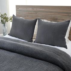 a bed with two pillows on top of it and a wooden headboard behind it