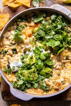 a casserole dish with spinach, cheese and other toppings on a cutting board