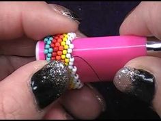 someone is doing something with some beads on their nails and they are holding a pink pen