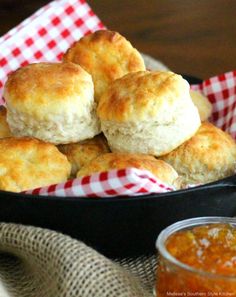 some biscuits are in a black bowl with a red and white checkered napkin next to it