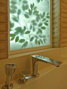 a bathroom sink under a window with green leaves on the glass and water running down it