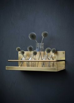 a metal shelf with vases and flowers in it on a black wall next to a pair of scissors