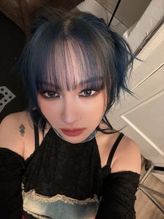 a woman with blue hair and piercings posing for the camera in a black top