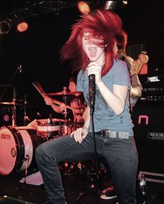 a woman with red hair singing into a microphone