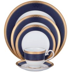 the blue and gold dinnerware is set with two cups, one saucer and one plate