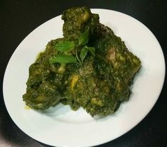 a white plate topped with broccoli covered in pesto