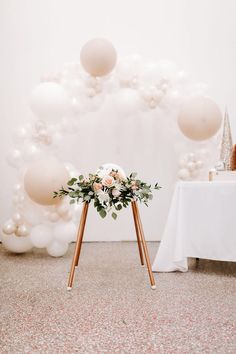 a table with balloons and flowers on it in front of a white backdrop at a wedding