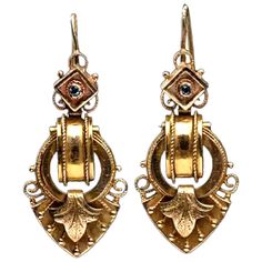 A pair of Renaissance Revival style drop earrings set in 14 Karat yellow gold. Circa 1860-1880. Each earring featuring a diamond shaped top embellished with a bezel set round mixed cut blue saphire. Surmounting an articulated drop featuring a beaded oval link connected within a beaded circular link. The earrings come to a point embellished by a stylized stippled and etched leaf flanked by beaded scrolls and further embellished with granulation work. Long wire in the backs. measurements: 1 7/8” l Ancient Earrings, Victorian Gold Earrings, 1800s Jewelry, Tara Shaw, Mughal Jewelry, Coral Drop Earrings, London Painting, Yellow Gold Drop Earrings, Vintage Drop Earrings