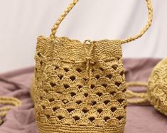 a crocheted straw bag sitting on top of a pink cloth covered tablecloth