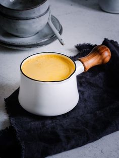 a white bowl filled with yellow liquid on top of a black towel