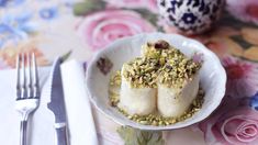 two pieces of food in a white bowl on a floral table cloth with silverware