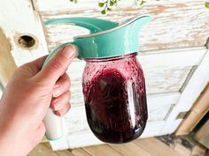 a person holding a glass jar with liquid in it and a bottle opener attached to the lid