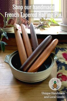 a bowl filled with wooden spoons sitting on top of a table next to a window