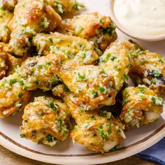 a white plate topped with fried food next to a bowl of ranch dressing