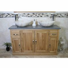 two white bowls on top of a wooden vanity