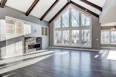 an empty living room with wood floors and large windows in the ceiling, along with built - in shelving