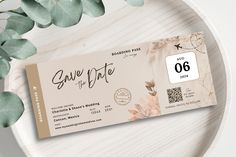 a wedding save the date ticket sitting on top of a plate next to eucalyptus leaves