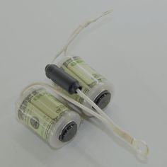 two batteries with wires attached to them sitting on a table next to some money bills