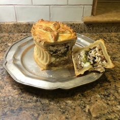 a pie sitting on top of a metal plate next to a muffin cut in half