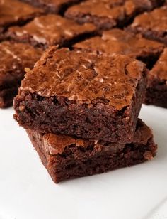 chocolate brownies stacked on top of each other on a white plate with one cut in half