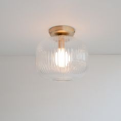 a clear glass light fixture hanging from the ceiling in a room with white walls and flooring