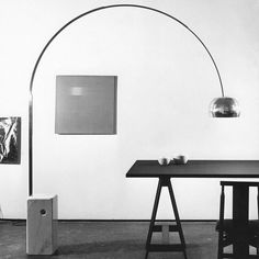 a black and white photo of a table with a lamp on it in an empty room