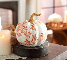 a white and orange pumpkin sitting on top of a wooden table next to two candles