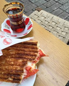 a grilled cheese sandwich on a plate next to a cup of coffee