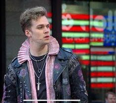 a man wearing a leather jacket standing in front of a building with words on it