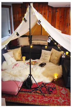 a living room with a couch, rug and lights on the wall above it is decorated in white