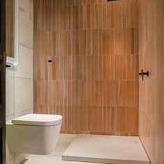 a bathroom with a toilet and tiled walls