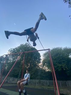 two people are hanging upside down on a swing set and one is holding onto another person's leg