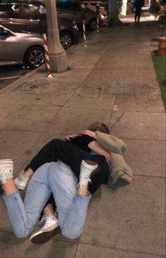 two people laying on the sidewalk with their arms around each other