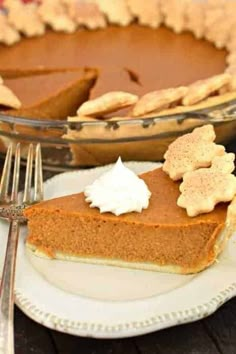 a slice of pumpkin pie on a plate next to a fork and glass bowl with whipped cream